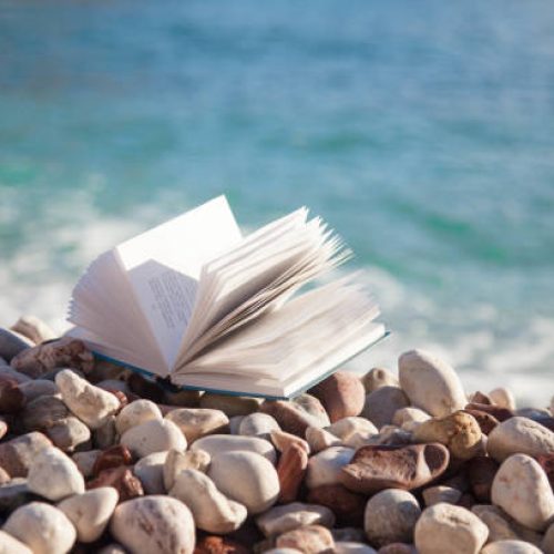 Book on sea beach. Concept of reading paper book, relaxation in holidays, enjoying summer vacation.